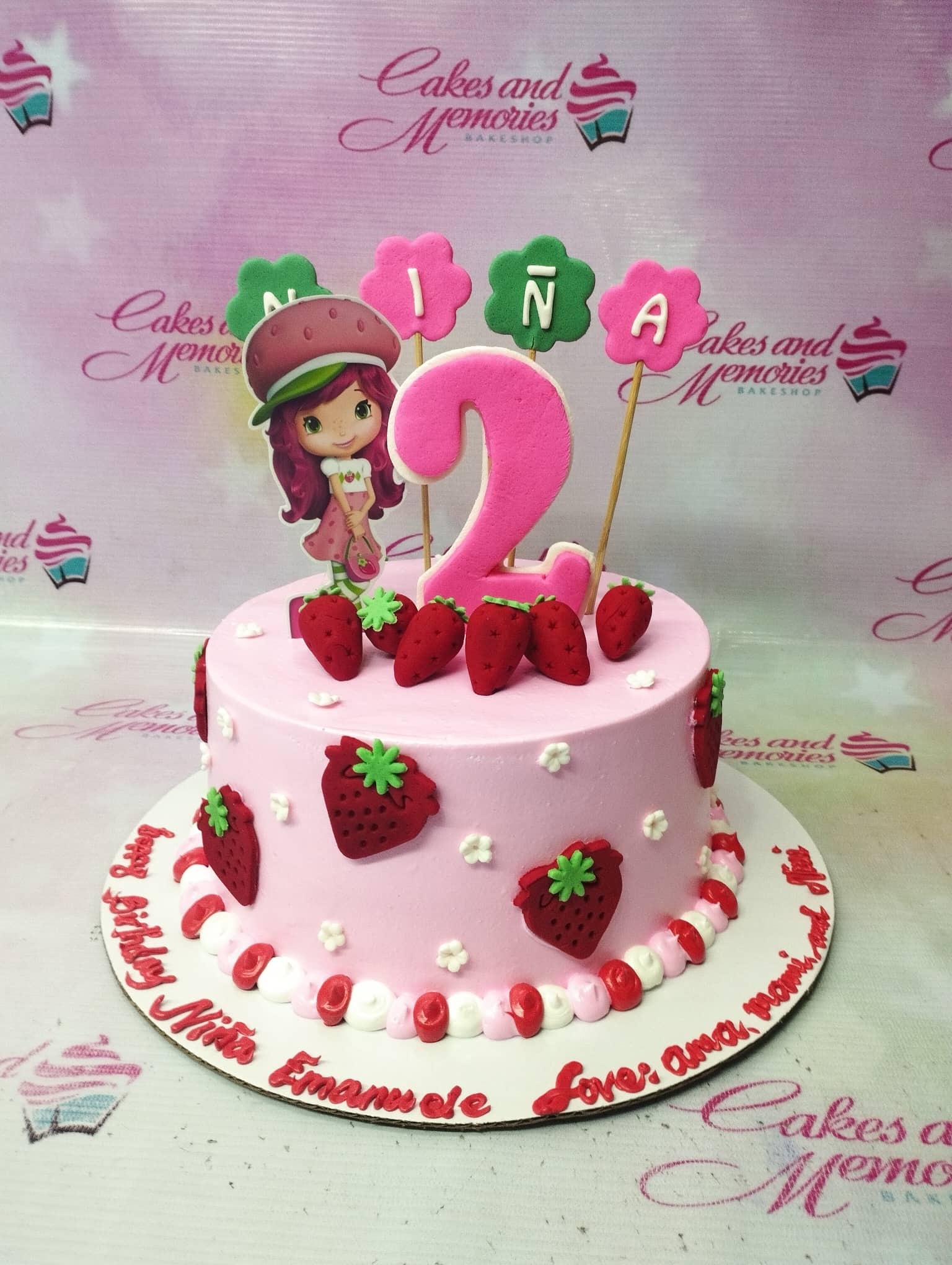 Pink Strawberry Shortcake themed birthday cake with character printout, fondant strawberries, and a large pink number 2 topper.