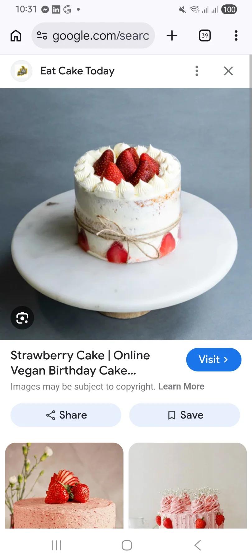 Semi-naked strawberry birthday cake with fresh strawberry slices and white icing rosettes on a marble stand.