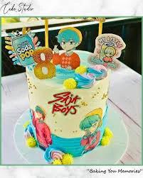 Stray Boys themed birthday cake with blue and white icing, character printouts, and a gold glitter number 8 topper.