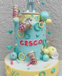 Light blue fondant cake with K-pop theme featuring 3D figures, soda cans, and colorful rings for a birthday celebration.