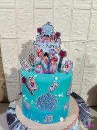 Teal blue Stray Kids K-pop themed birthday cake with character printouts, music notes, and lightstick decorations.