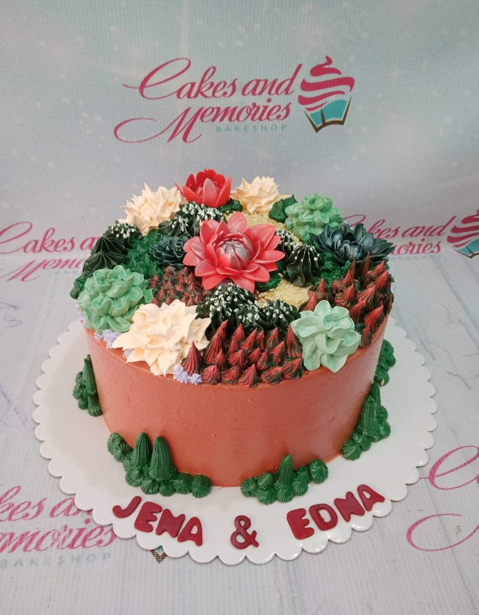 Succulent garden cake with terracotta orange icing and various piped green and pink succulent plants on top.
