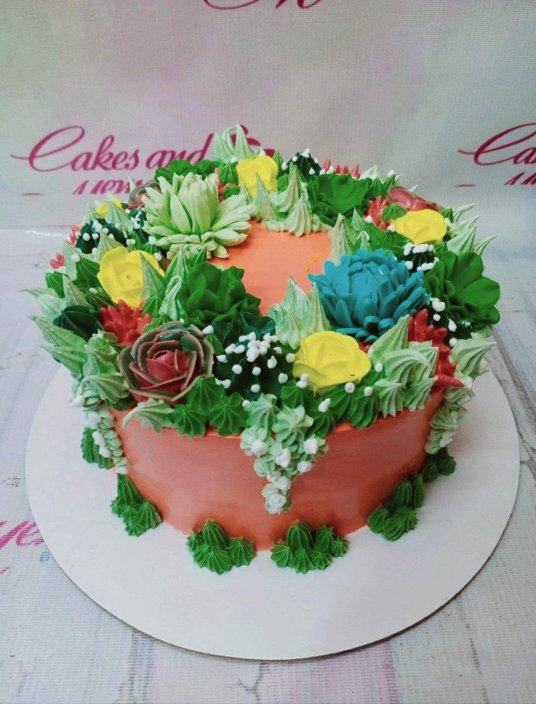 Orange round cake topped with a dense garden of green, yellow, and red succulent-style icing rosettes and flowers.