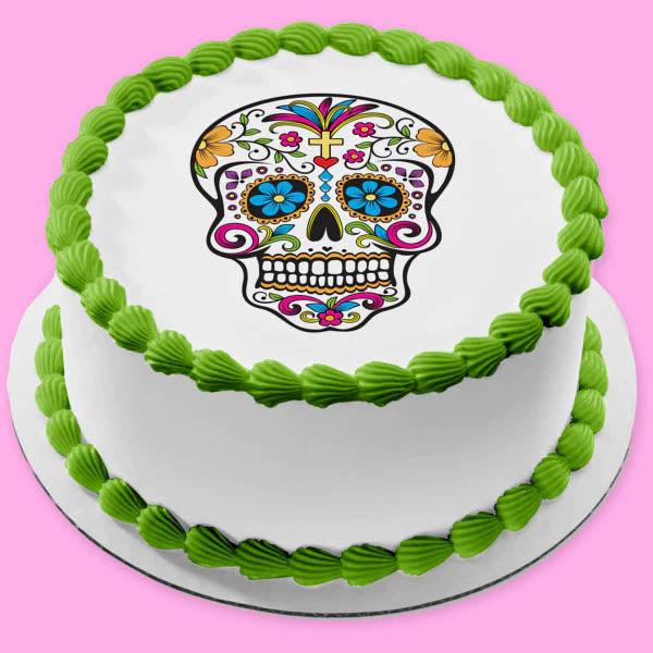 White round cake with a colorful Day of the Dead sugar skull print and green icing shell borders.