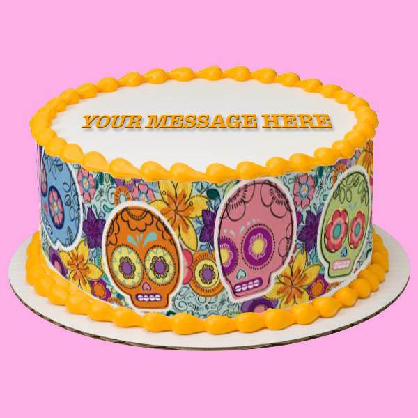 Round white cake with orange icing borders and a colorful Day of the Dead sugar skull side wrap.
