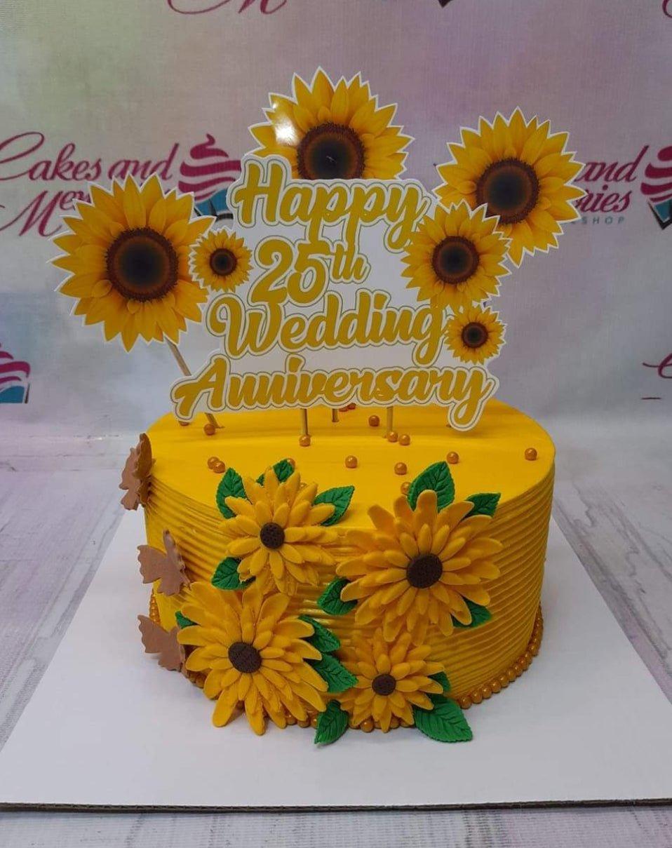 Yellow sunflower themed 25th wedding anniversary cake with large sunflower toppers and gold dragees.