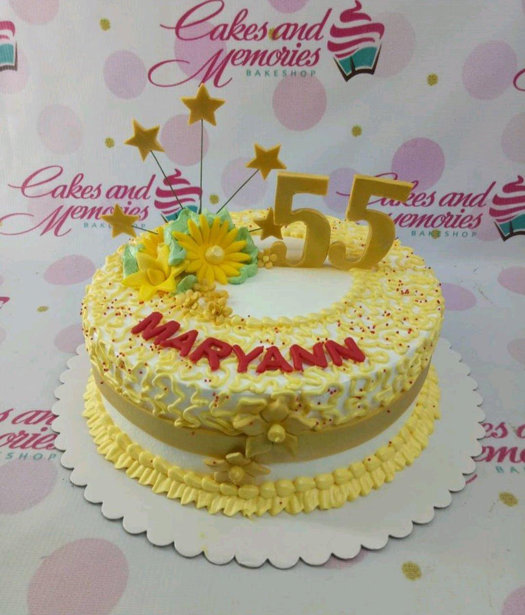 Yellow and white 55th birthday cake with sunflowers, gold stars, and red icing text.