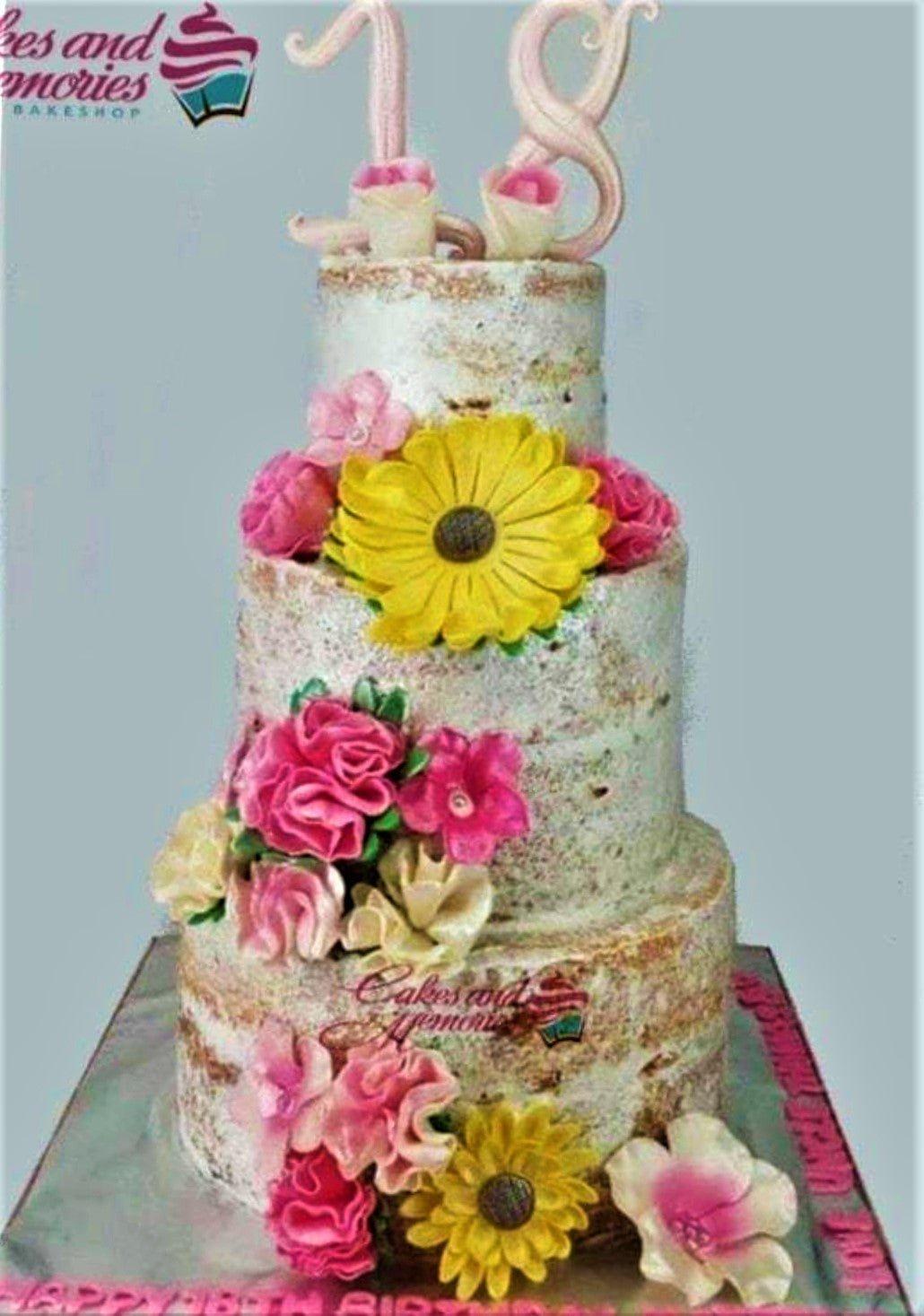 Three-tier semi-naked birthday cake decorated with vibrant yellow sunflowers and pink gumpaste flowers for an 18th birthday celebration.