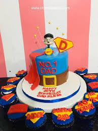 Blue and brown superhero dad cake with a red fondant cape, a 3D dad figure, and matching cupcakes.
