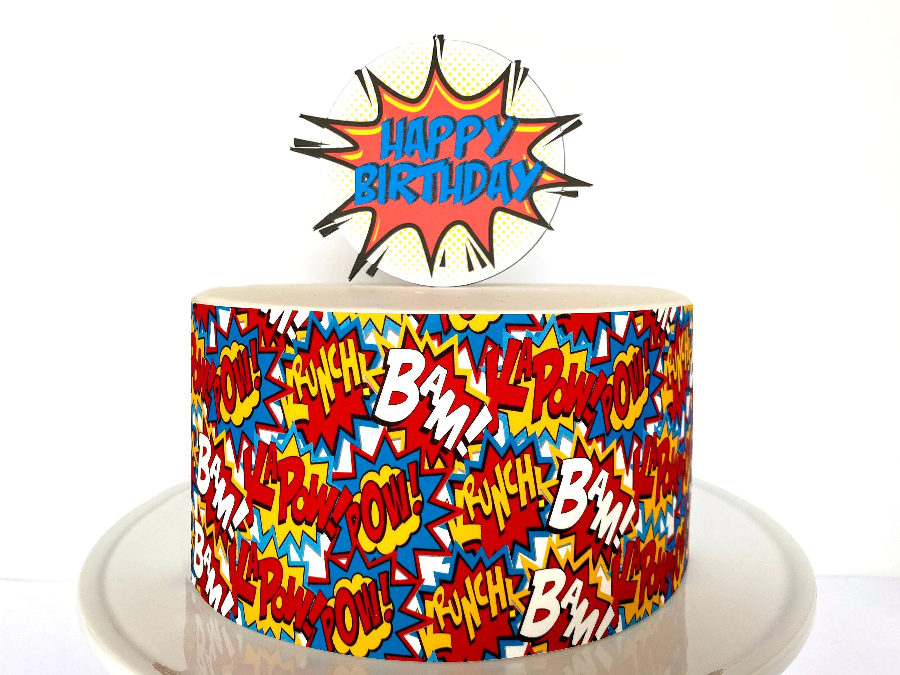 Superhero comic book themed birthday cake with colorful BAM and POW graphics and a Happy Birthday topper.