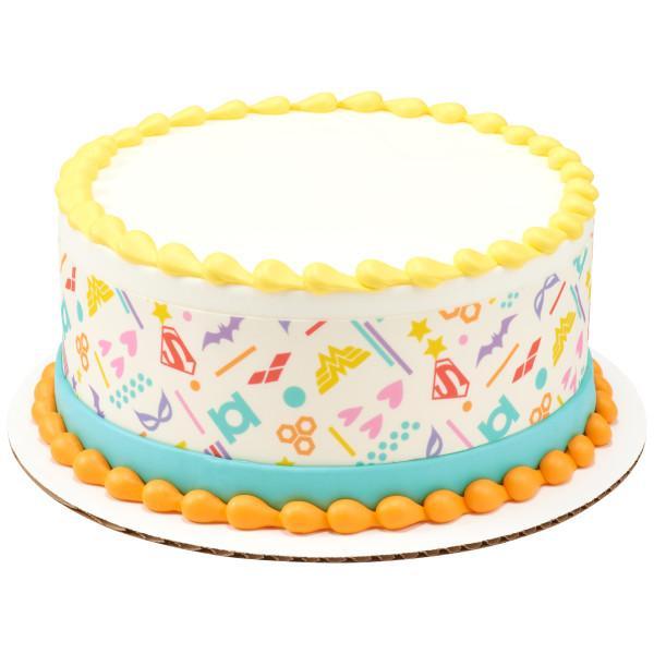 White round cake with colorful superhero logo side wrap, yellow top border, and orange base border.