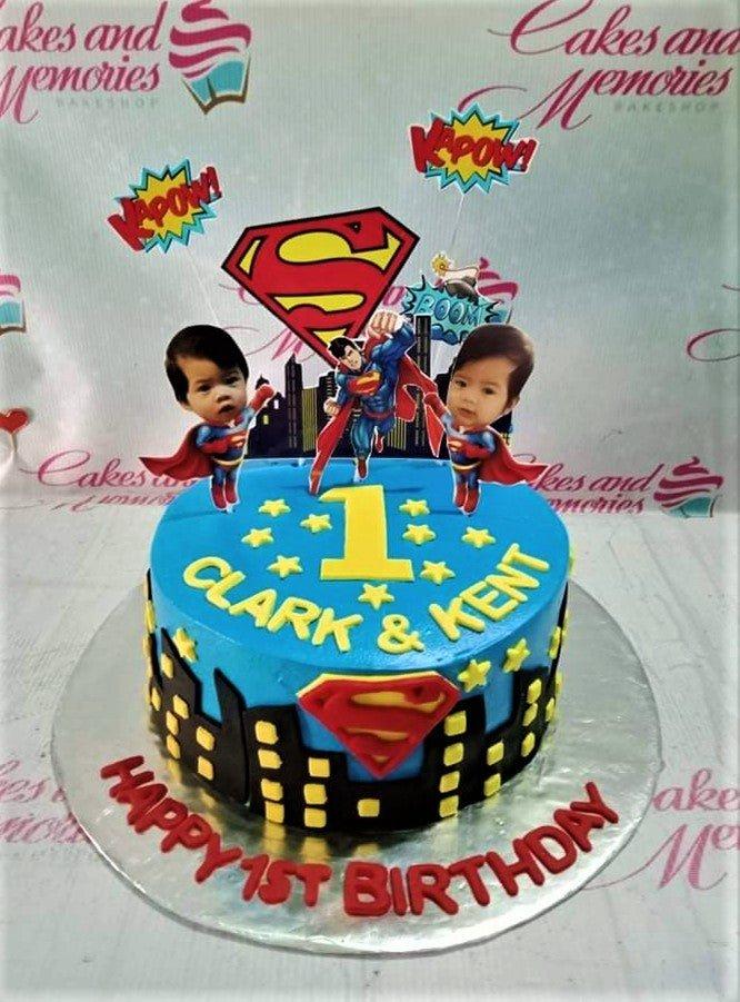Superman themed birthday cake for Clark and Kent with city skyline and character toppers