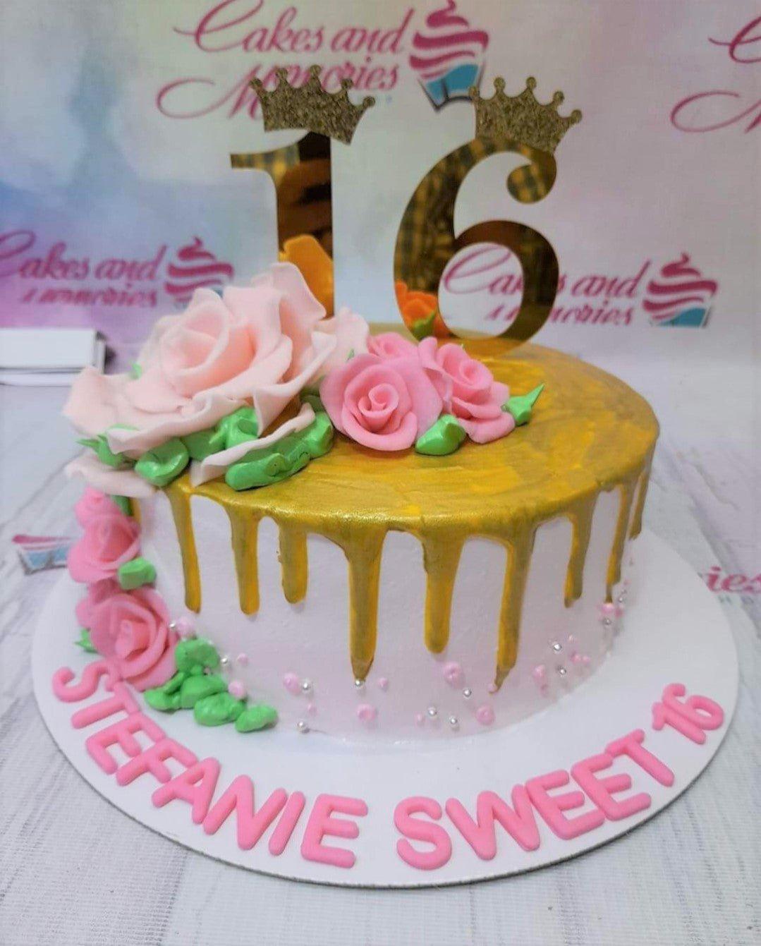 White 1-tier cake with gold drip, pink fondant roses, and a gold number 16 crown topper.