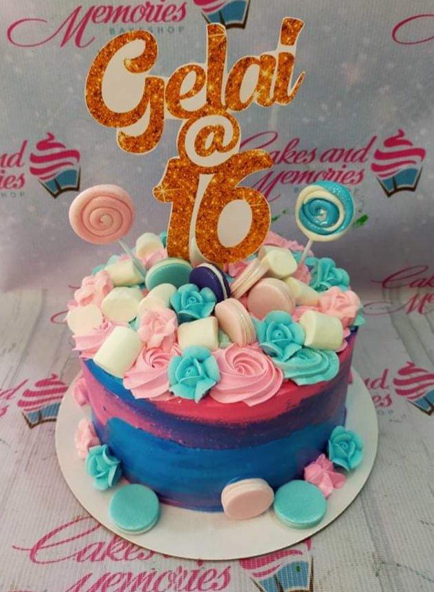 Pink and blue gradient cake with gold glitter Gelai at 16 topper, macarons, marshmallows, and icing roses.