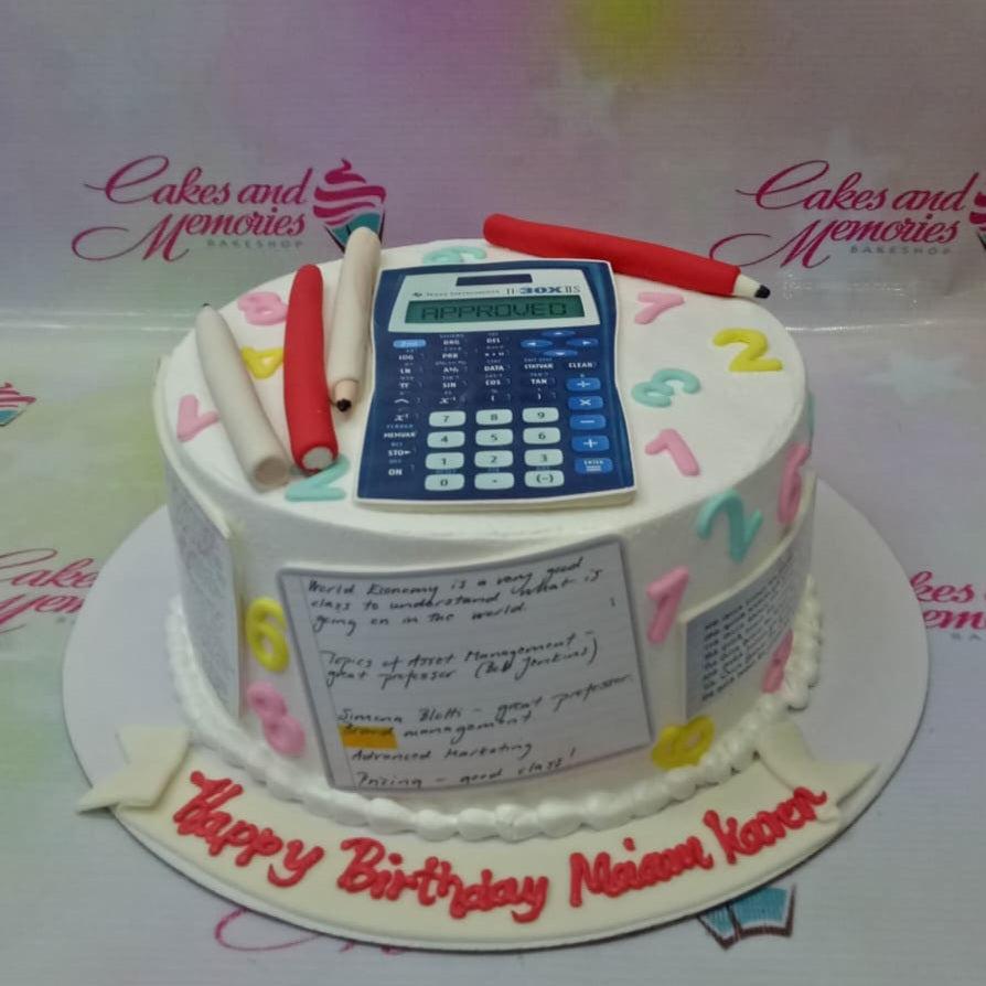 White round cake with a blue calculator topper, red and white pencils, and colorful numbers for a teacher's birthday.