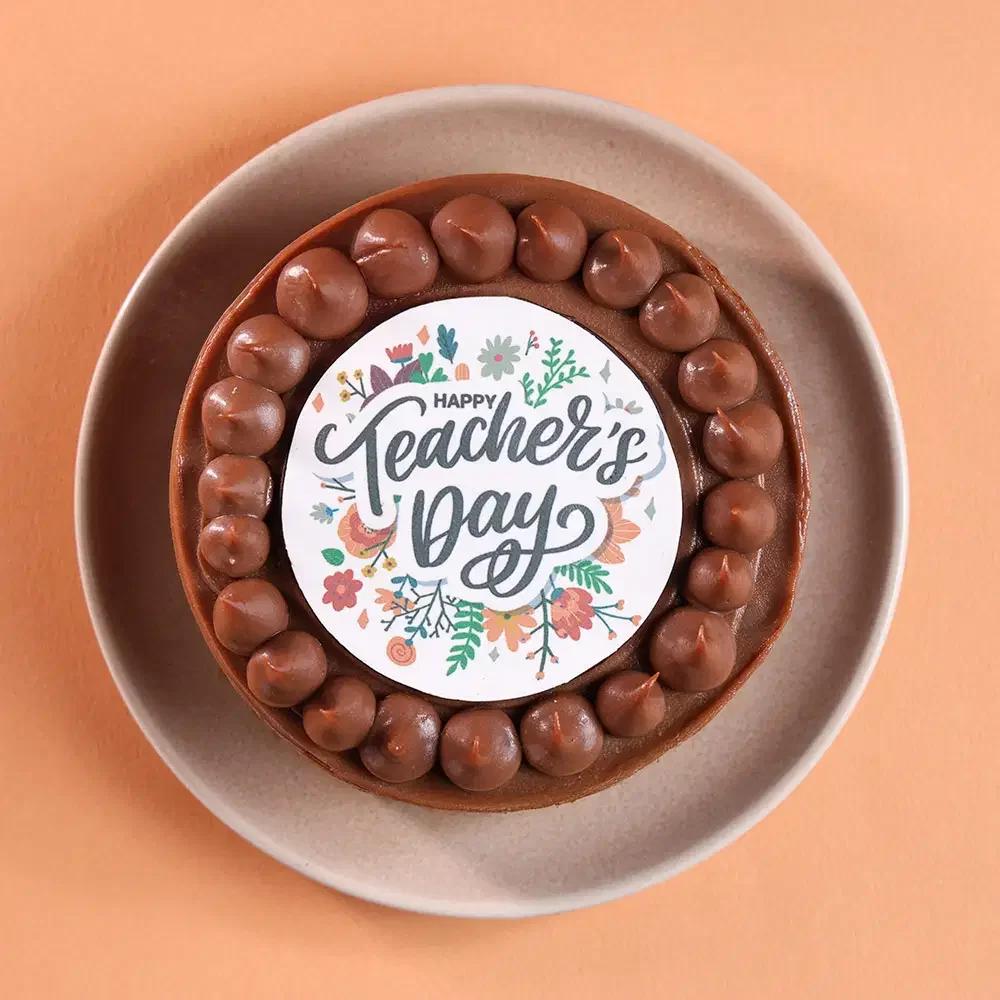 Chocolate bento cake with brown icing dollops and a floral Happy Teacher's Day printout topper.