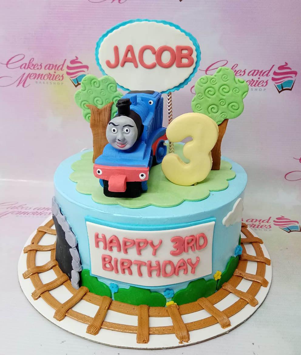 Thomas the Tank Engine themed blue fondant cake with a 3D train topper, gumpaste trees, and a train track on the base board.