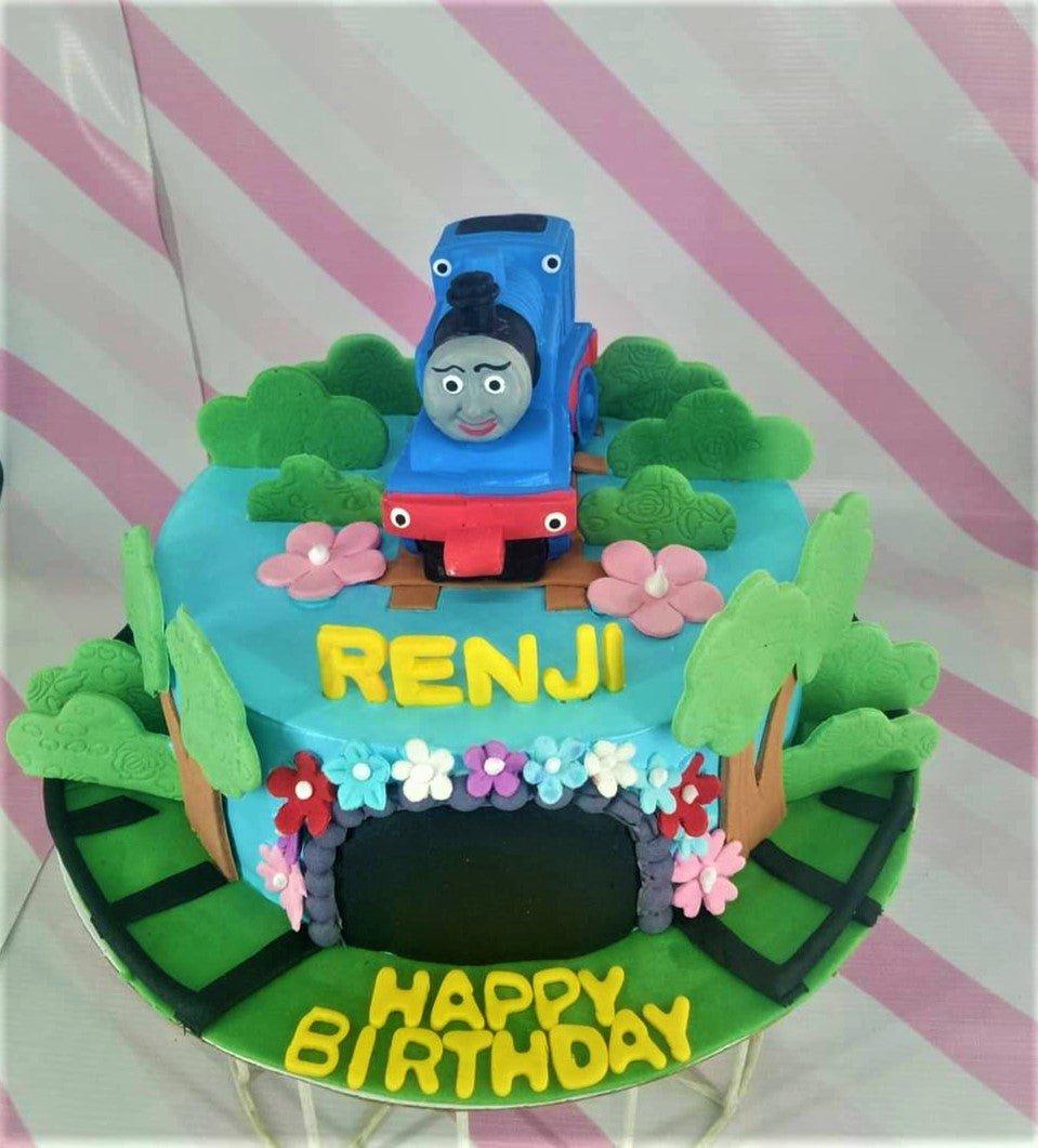 Thomas the Tank Engine themed blue fondant cake with 3D train topper, edible trees, and a tunnel design.