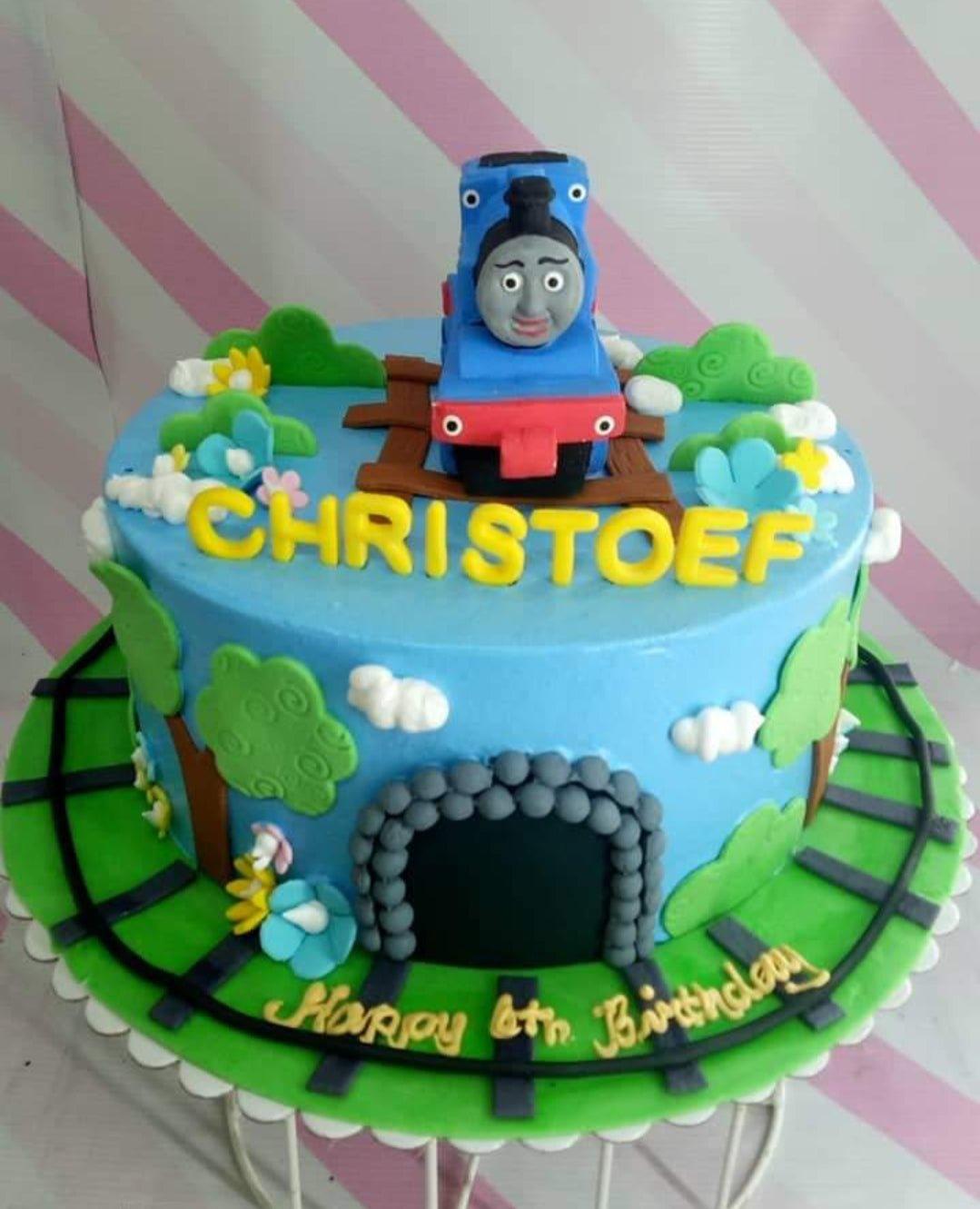 Thomas the Tank Engine themed blue fondant cake with a 3D train topper, tunnel, and green grass base board.
