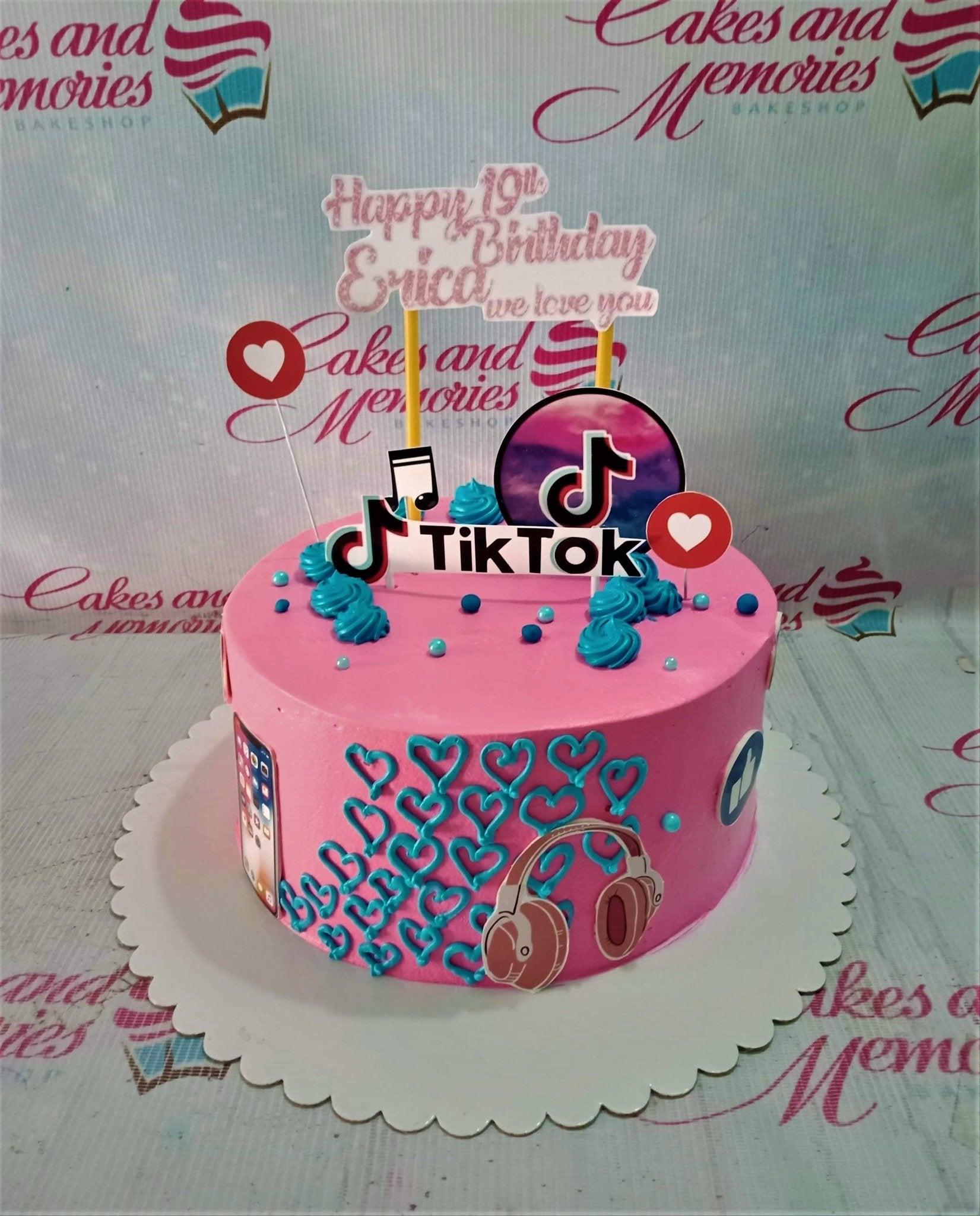 Pink TikTok themed birthday cake with teal icing hearts, headphones, and social media icons for a 19th birthday celebration.