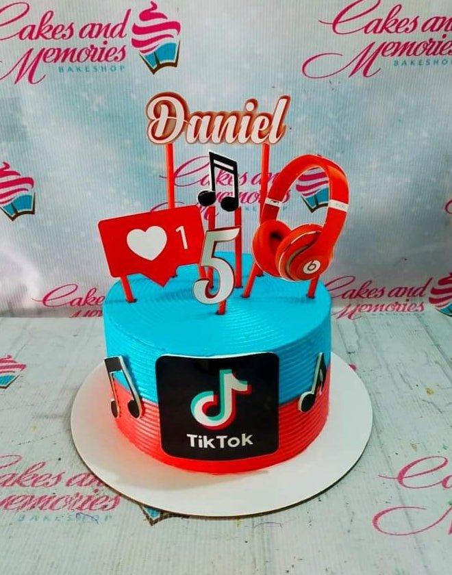 Blue and red TikTok themed birthday cake with headphones, music notes, and a personalized name topper for Daniel.