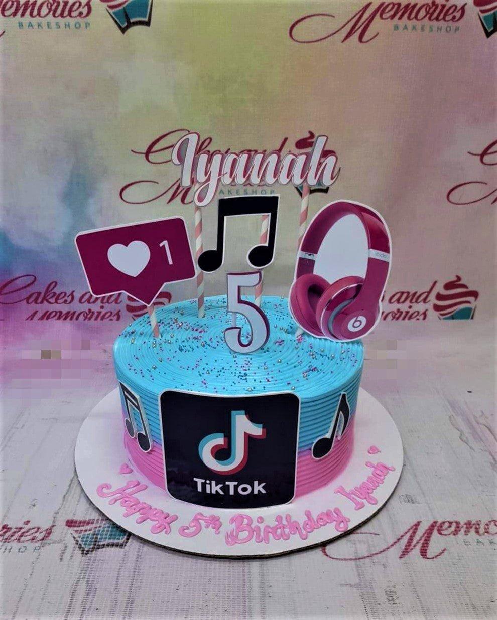 Blue and pink TikTok themed birthday cake with music notes, headphones, and a like icon topper for Iyanah's 5th birthday.