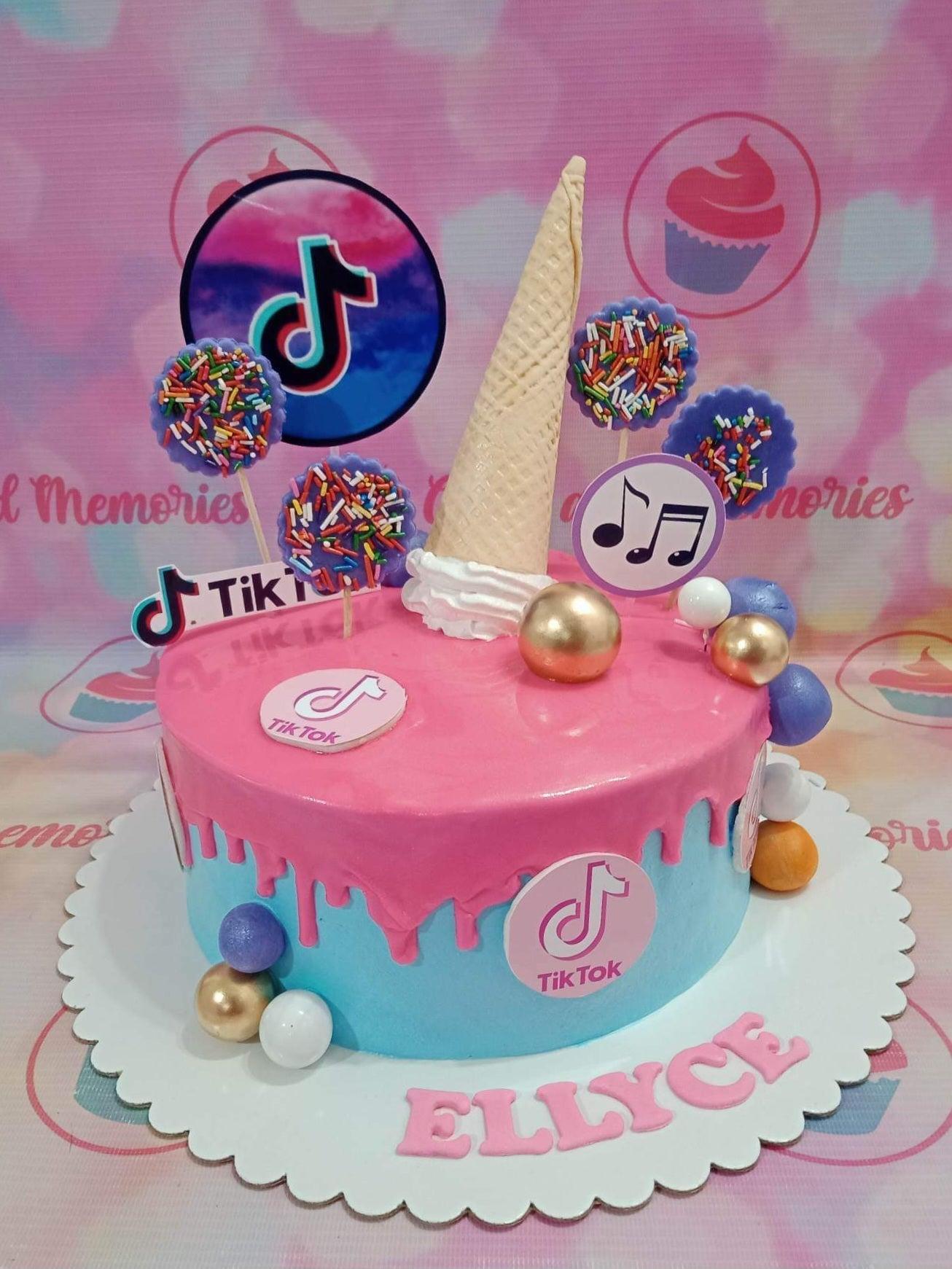 Pink and blue TikTok themed birthday cake with a pink drip, ice cream cone topper, and musical note decorations.