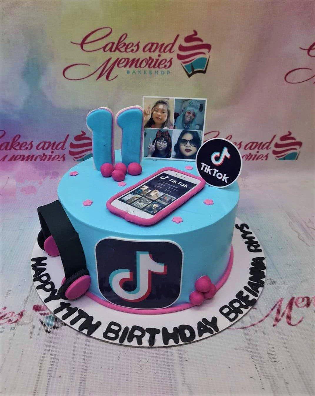 Light blue TikTok themed birthday cake with a fondant smartphone, headphones, and printed character photos.