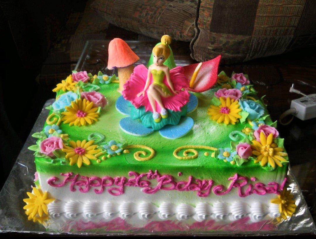 Tinkerbell themed rectangle birthday cake with green and white icing, colorful fondant flowers, and a Tinkerbell figurine topper.