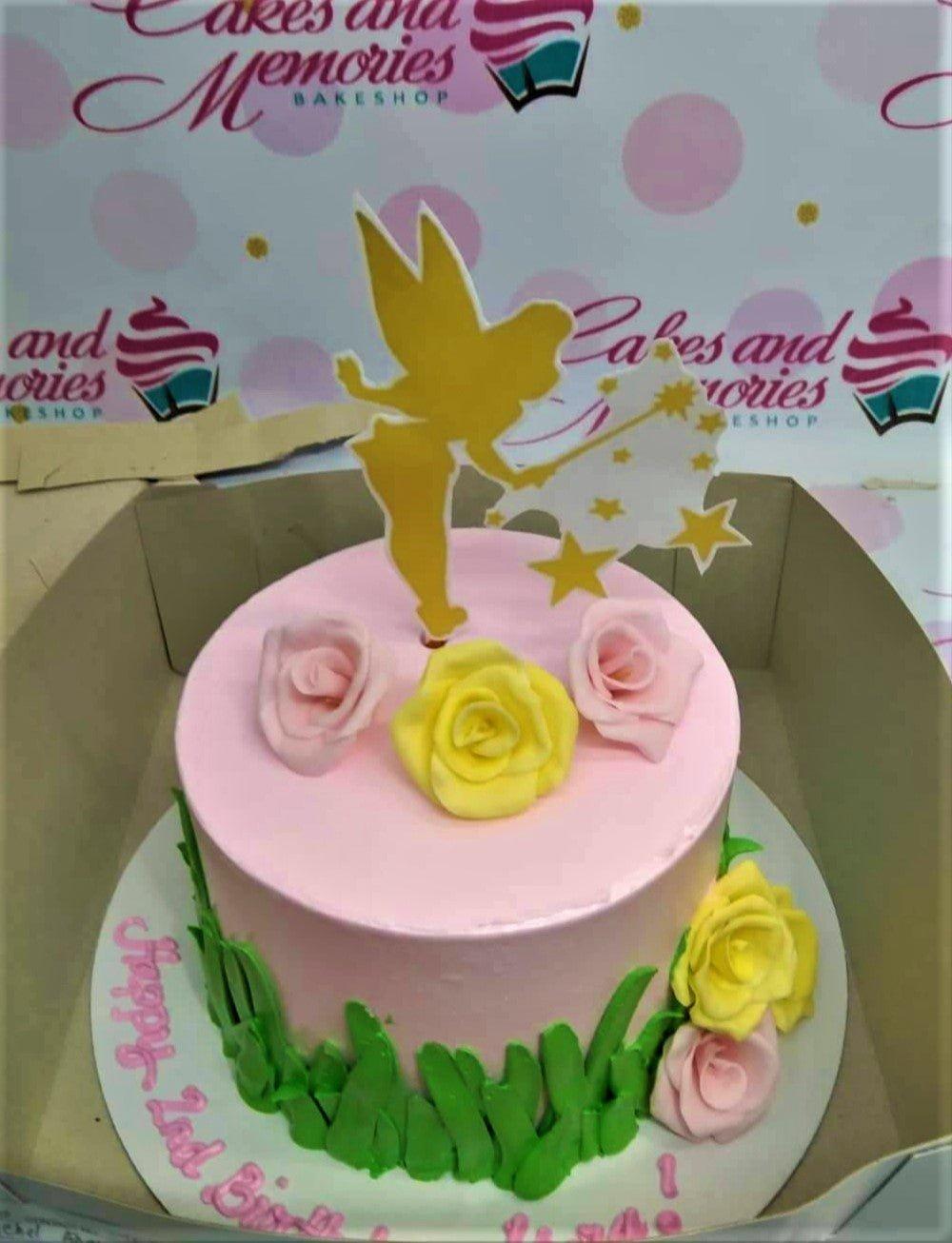 Pink Tinkerbell themed birthday cake with yellow and pink fondant roses and green grass icing decorations.