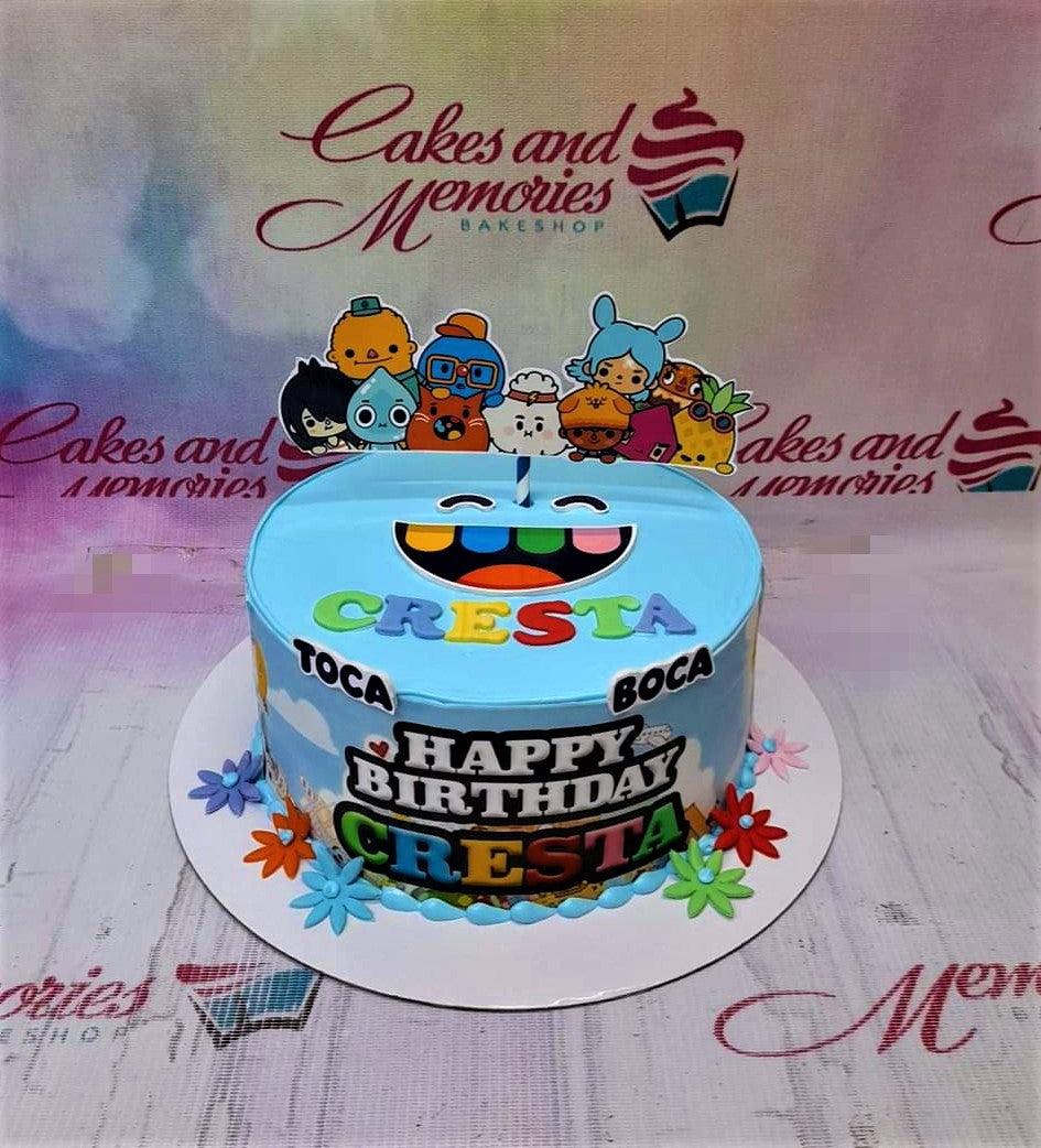 Light blue Toca Boca themed birthday cake for Cresta featuring colorful character printouts and fondant flowers.
