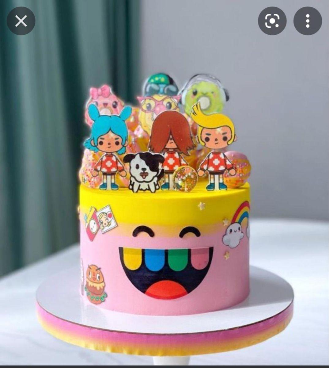 Toca Boca themed birthday cake with yellow and pink gradient icing, character printouts, and a large smiling face design on the side.