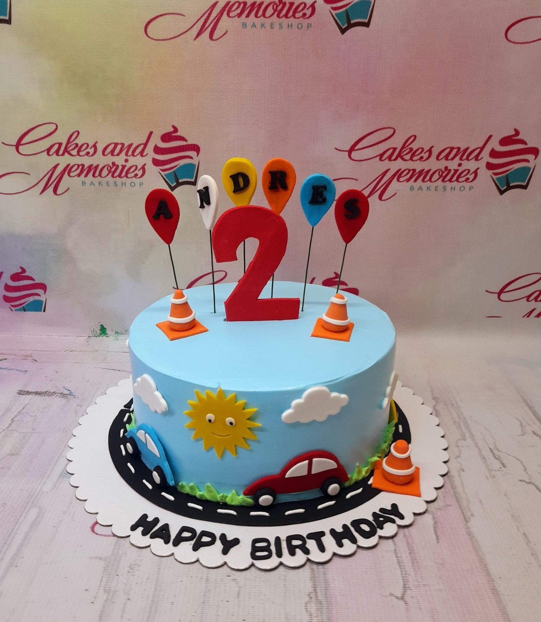 Light blue 1-tier transportation themed birthday cake with a large red number 2, balloon toppers, and car decorations.