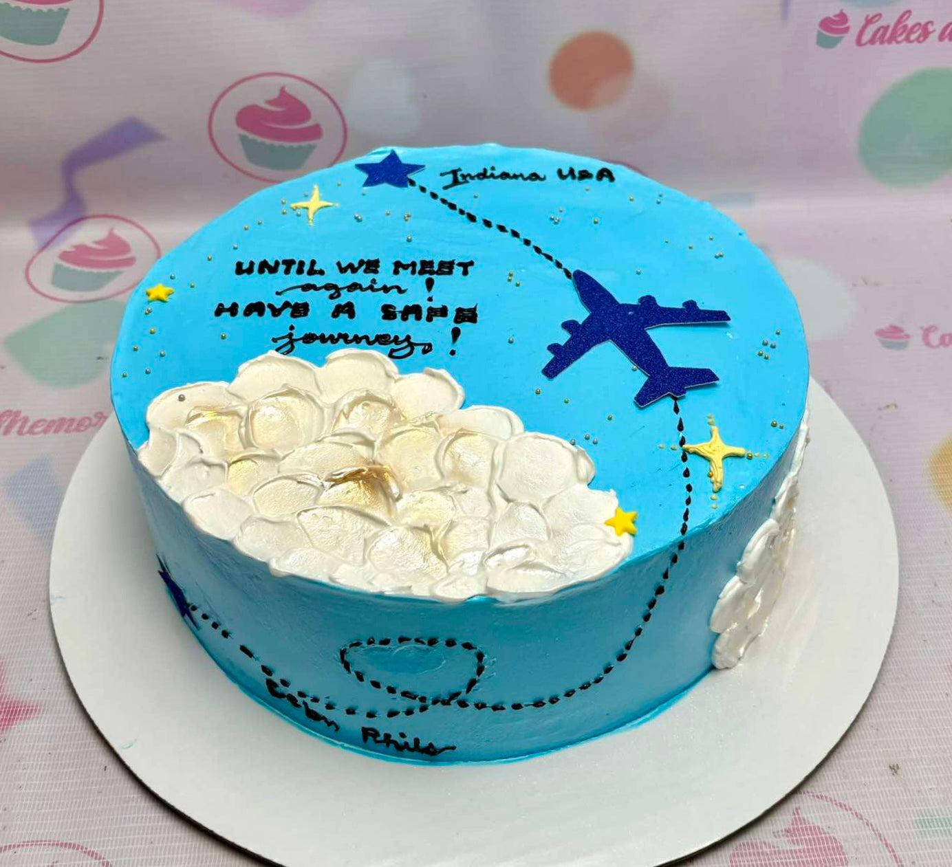 Light blue travel themed cake with a dark blue airplane, white palette knife clouds, and a message for a safe journey.