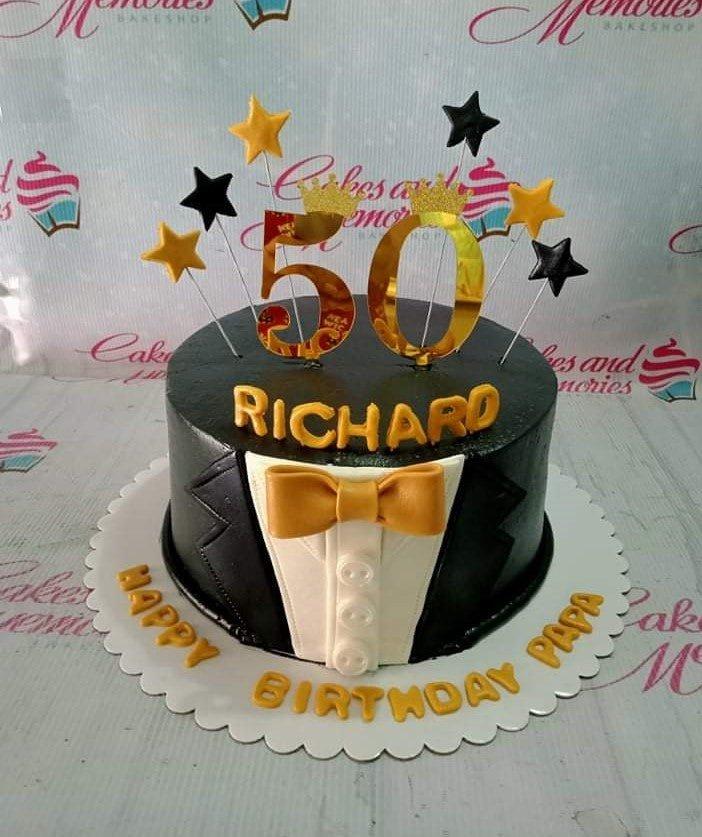 Black tuxedo themed 50th birthday cake with gold bow tie and gold star toppers