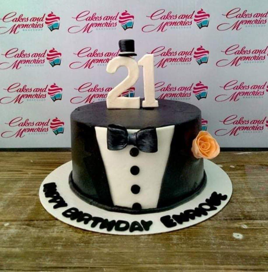Black and white tuxedo themed birthday cake with a white number 21 topper and a small top hat.