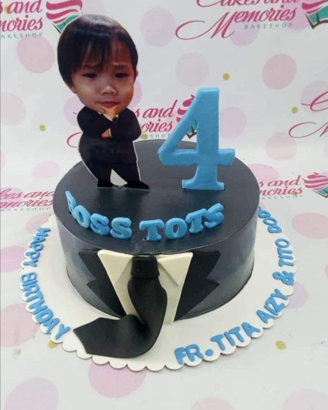Black tuxedo themed birthday cake with a 3D fondant tie and a personalized photo topper of a boy in a suit.