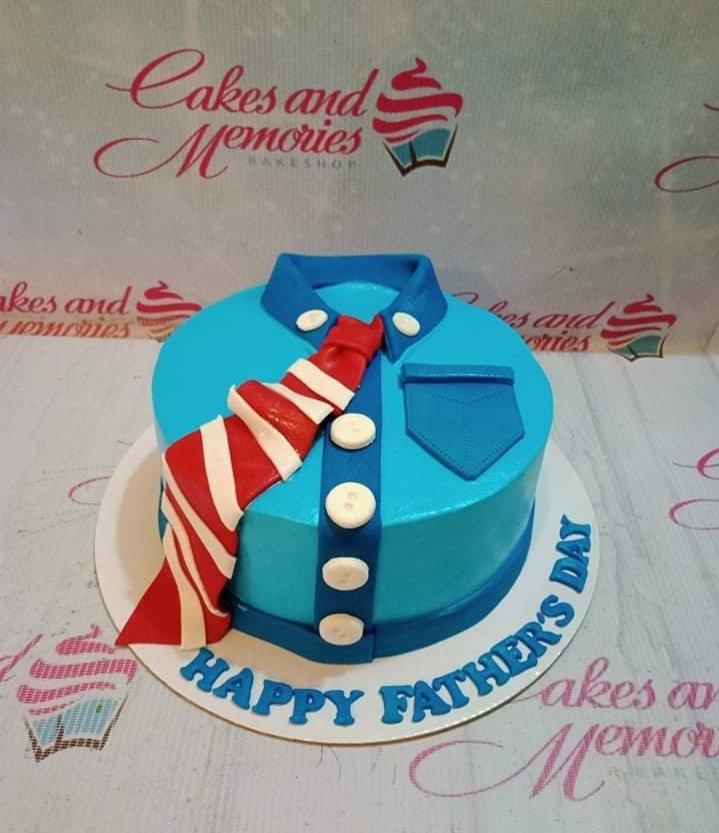Light blue tuxedo-themed cake with a red and white striped tie, blue pocket, and white buttons for Father's Day.