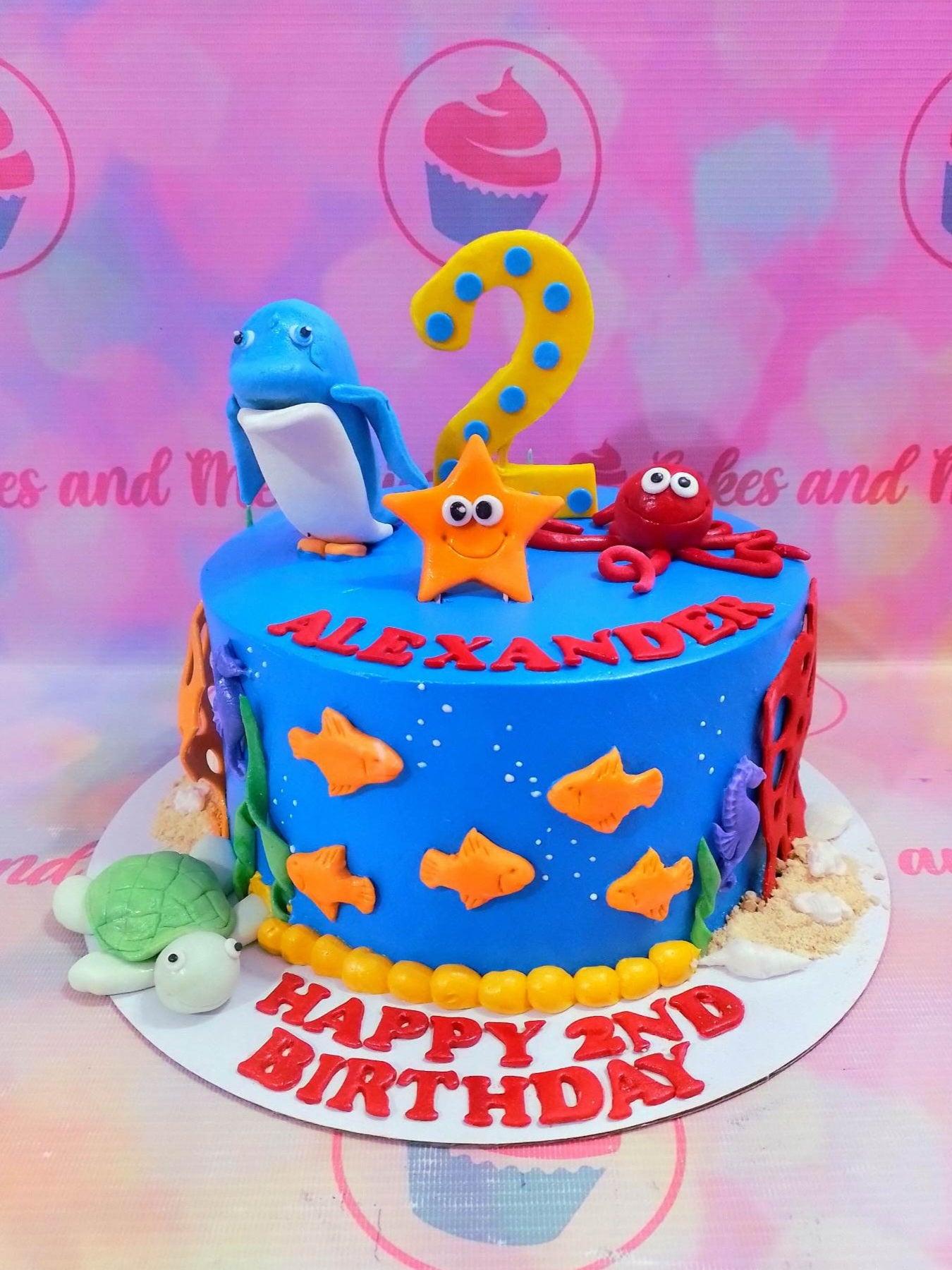 Blue underwater themed birthday cake for Alexander with fondant sea creatures including a turtle, octopus, starfish, and dolphin.