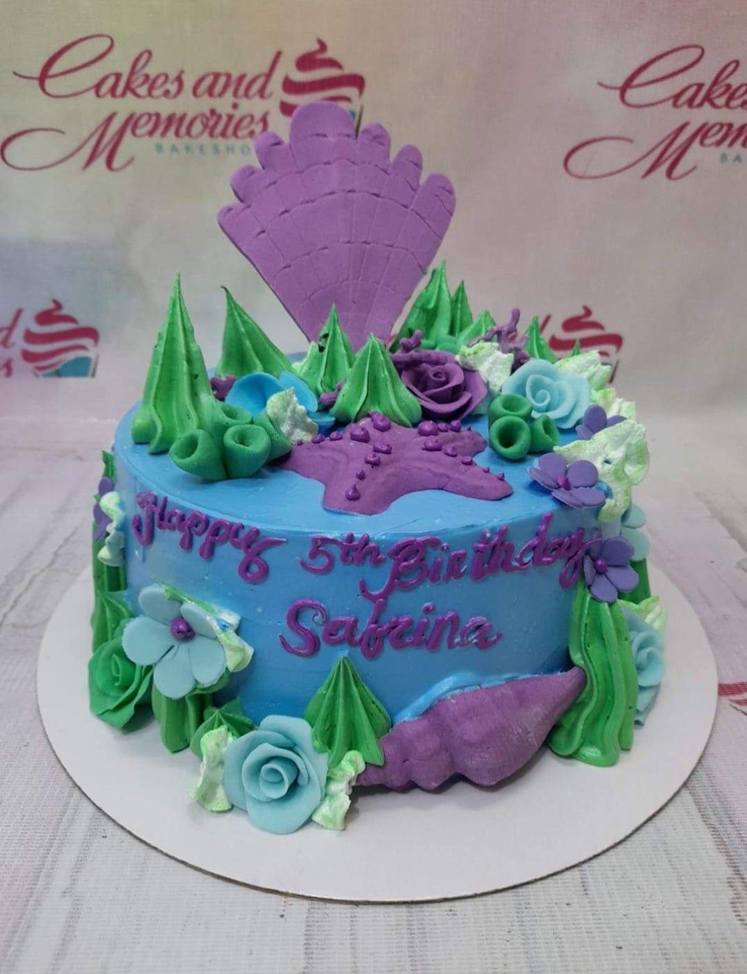 Under the sea themed blue cake with purple starfish, seashells, and green icing seaweed for Sabrina's 5th birthday.