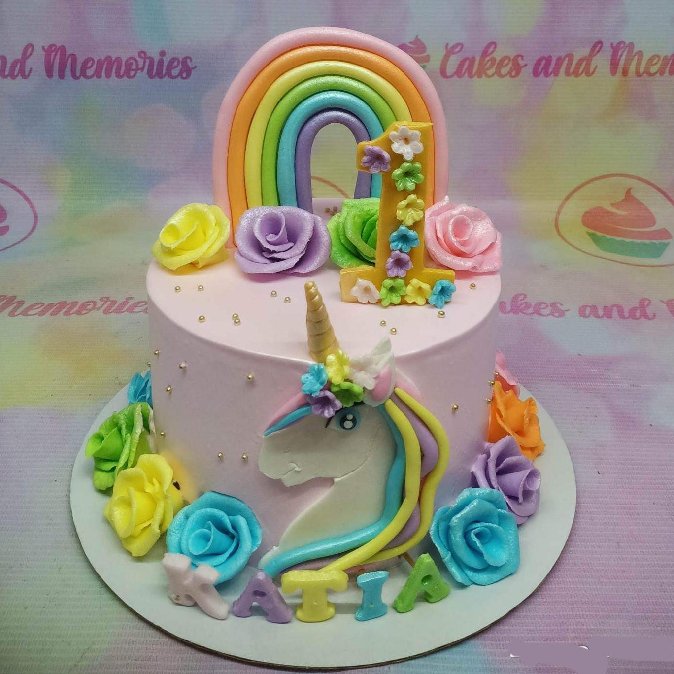 Pink unicorn birthday cake with a fondant rainbow, number one topper, and colorful gumpaste roses.