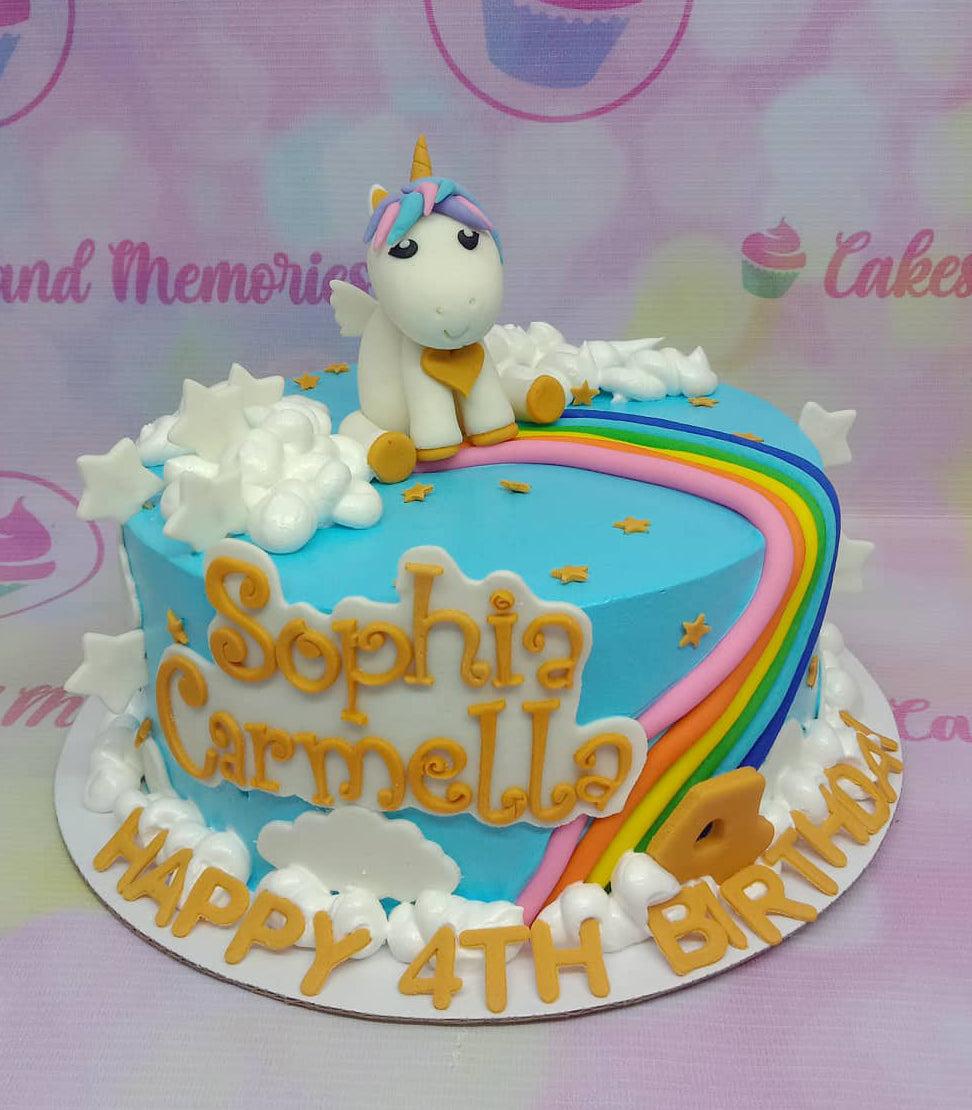 Light blue unicorn birthday cake with a fondant unicorn, rainbow, white clouds, and gold stars.