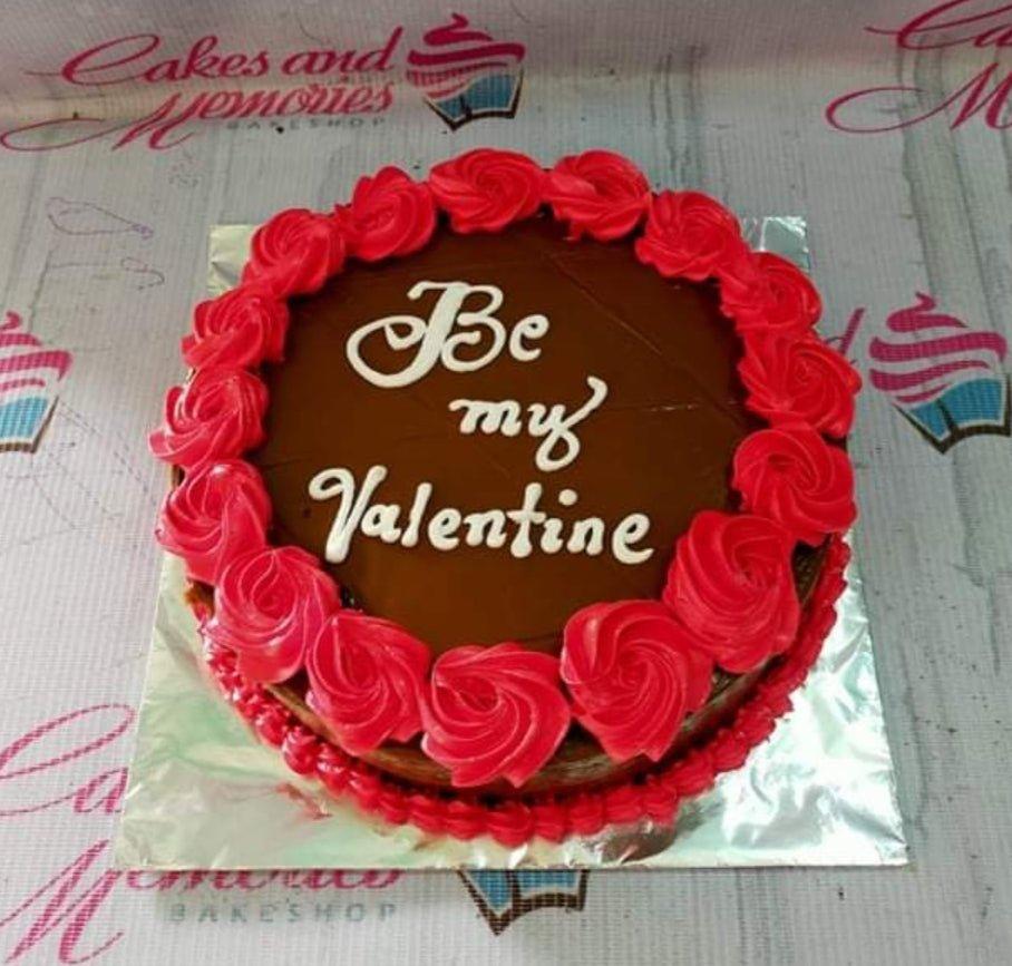 Chocolate cake with red icing rosettes and a white piped message saying Be my Valentine.