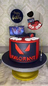 Red and black Valorant themed birthday cake with a gaming monitor topper, headset, and 3D letters on a black base board.