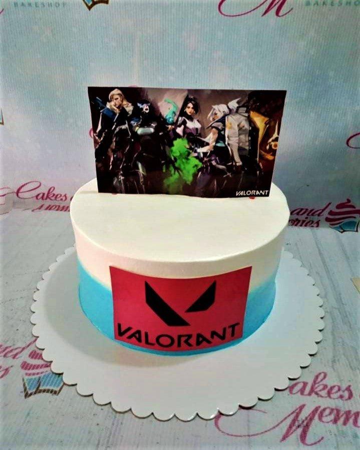 Valorant themed birthday cake with character printout and logo on a blue and white gradient icing base.