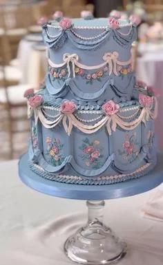 Elegant 2-tier light blue vintage cake with pink fondant roses, white icing swags, and pearl bead details.