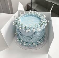 Light blue vintage style cake with intricate piped icing swags and white lily of the valley floral accents