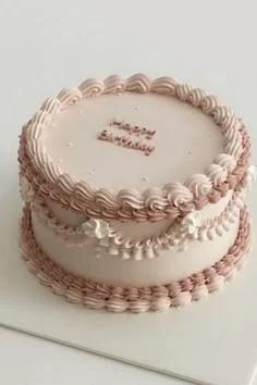 Elegant light pink vintage-style cake with intricate piped icing ruffles, swags, and a Happy Birthday message.