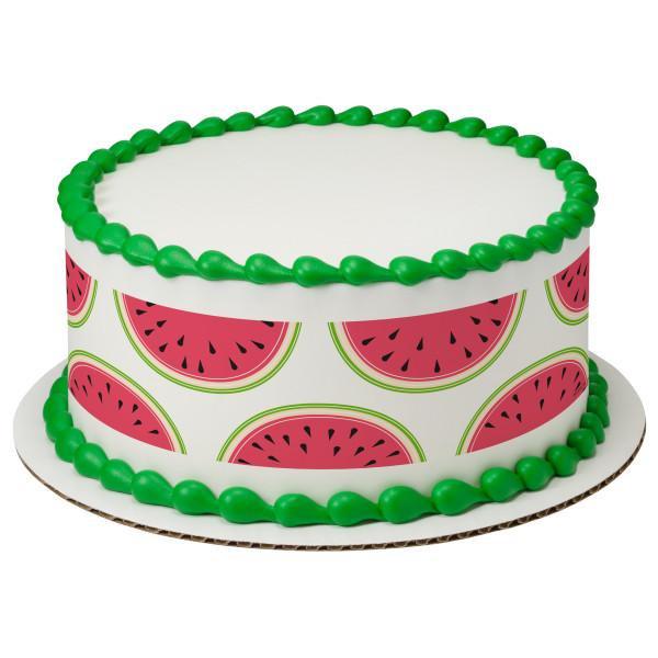 White round cake with green icing borders and a printed watermelon pattern on the sides.