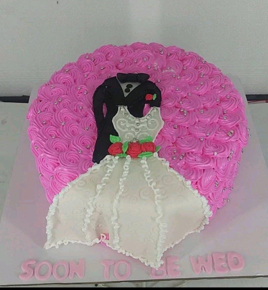 Pink rosette cake with a tuxedo and wedding dress design on top and a Soon To Be Wed message on the base board.